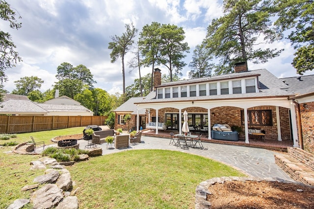 back of house featuring a patio area, a yard, and an outdoor living space with a fire pit