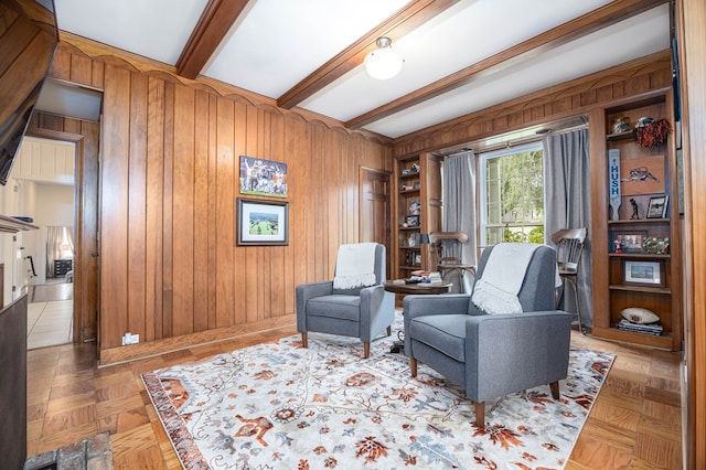 sitting room with parquet flooring, beamed ceiling, and wood walls