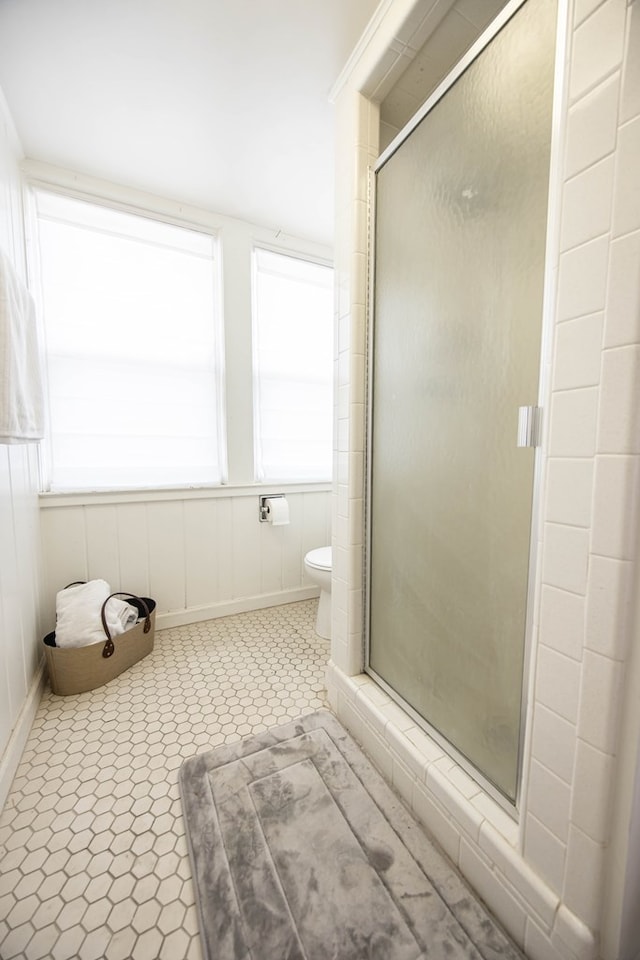 bathroom featuring a shower with shower door and toilet