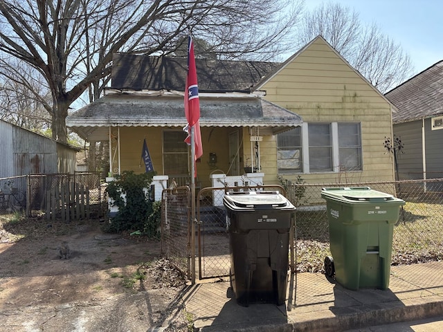 back of house with covered porch, fence, and a gate