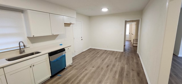 kitchen featuring a sink, light countertops, light wood-type flooring, white cabinetry, and stainless steel dishwasher