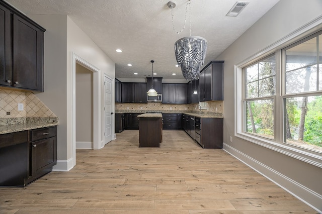 2708 Sawgrass Ln, Phenix City, AL 36867 - kitchen with backsplash, a center island, a sink, stainless steel microwave, and light wood-style floors
