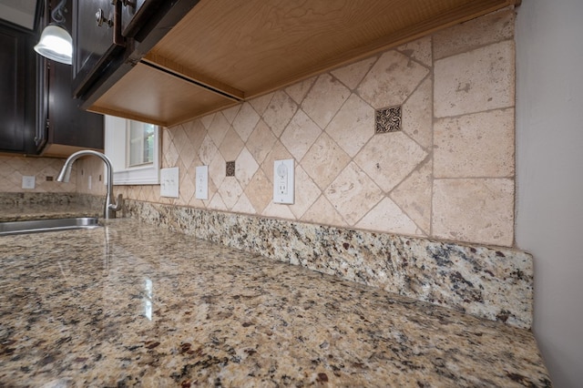 2708 Sawgrass Ln, Phenix City, AL 36867 - interior space featuring decorative backsplash, light stone countertops, dark cabinetry, a sink, and decorative light fixtures