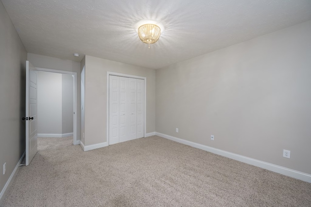 2708 Sawgrass Ln, Phenix City, AL 36867 - unfurnished bedroom with a notable chandelier, light carpet, a textured ceiling, baseboards, and a closet