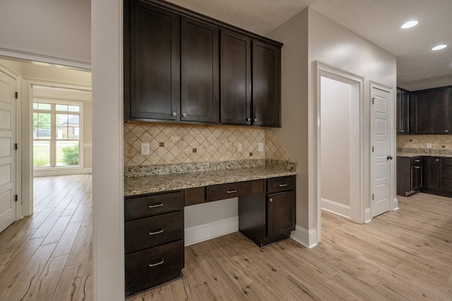 2708 Sawgrass Ln, Phenix City, AL 36867 - kitchen featuring decorative backsplash, dark brown cabinetry, baseboards, built in desk, and light wood-style flooring