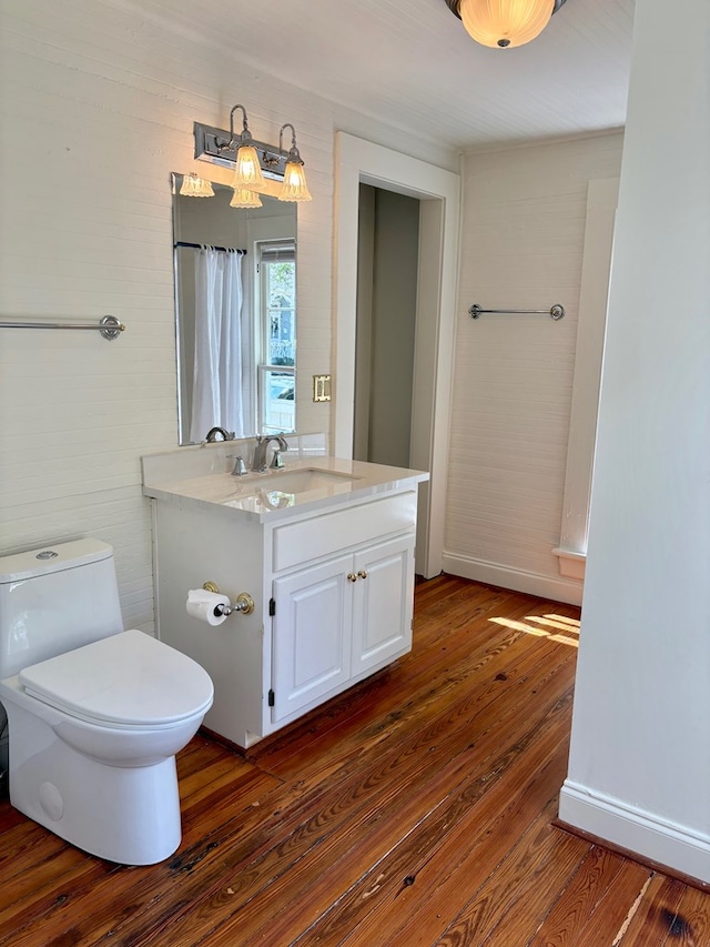 bathroom featuring wood-type flooring, toilet, vanity, and baseboards