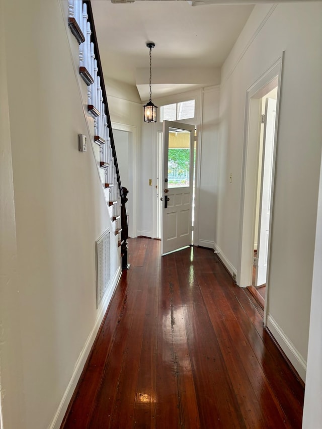 foyer entrance featuring visible vents, baseboards, dark wood-style flooring, and stairs