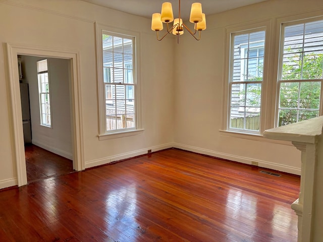 unfurnished dining area featuring baseboards, a notable chandelier, wood finished floors, and plenty of natural light