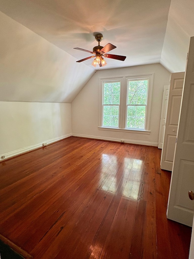 additional living space featuring dark wood finished floors, vaulted ceiling, a ceiling fan, and baseboards