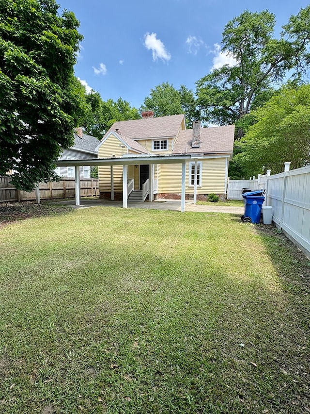 rear view of house with a yard, a fenced backyard, and a chimney