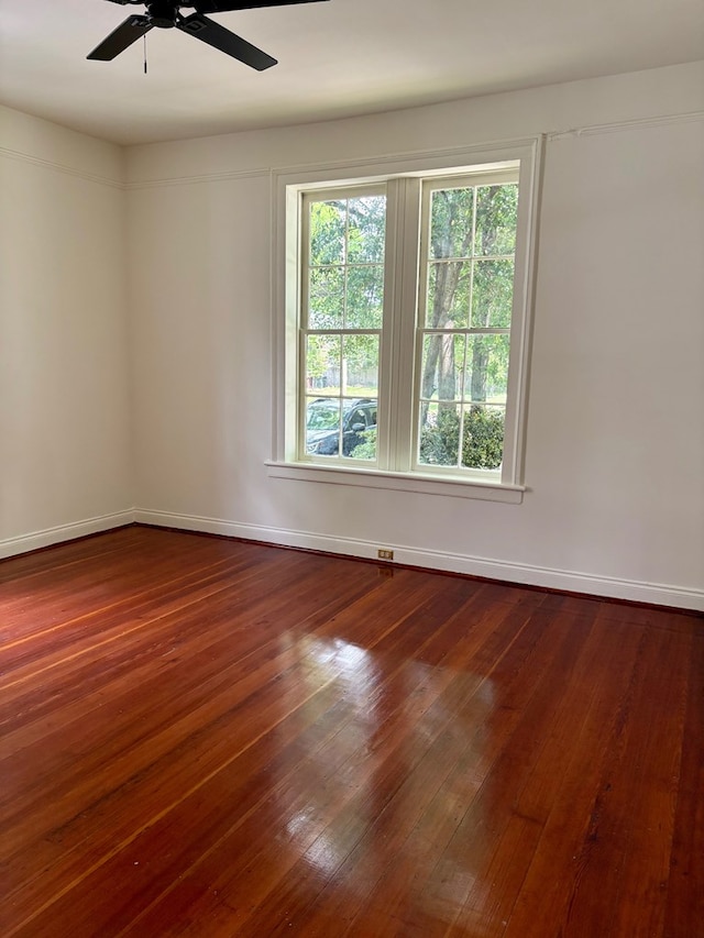 spare room featuring dark wood finished floors, baseboards, and ceiling fan