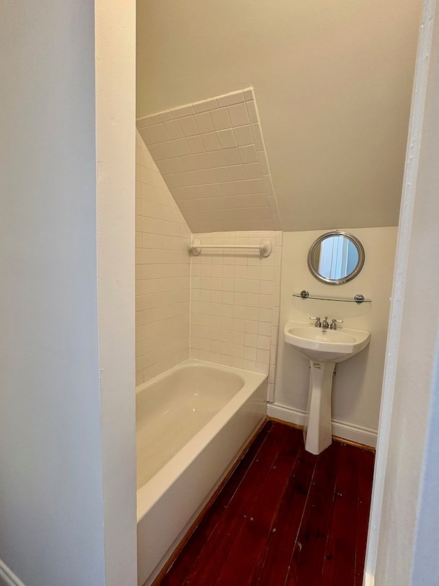 bathroom with vaulted ceiling, wood finished floors, and baseboards