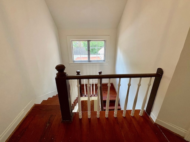 staircase featuring lofted ceiling, wood finished floors, and baseboards