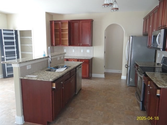 8 Rusty Dr, Phenix City, AL 36869 - kitchen featuring a sink, stainless steel appliances, dark brown cabinets, arched walkways, and a center island with sink