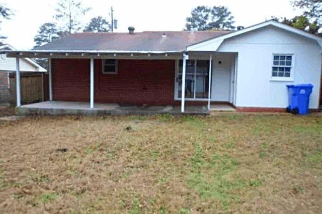 rear view of property featuring a lawn and a patio area