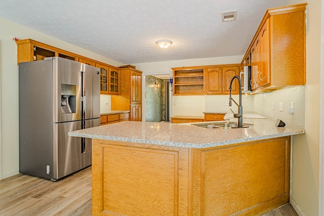 kitchen featuring stainless steel fridge, light wood finished floors, a peninsula, and open shelves