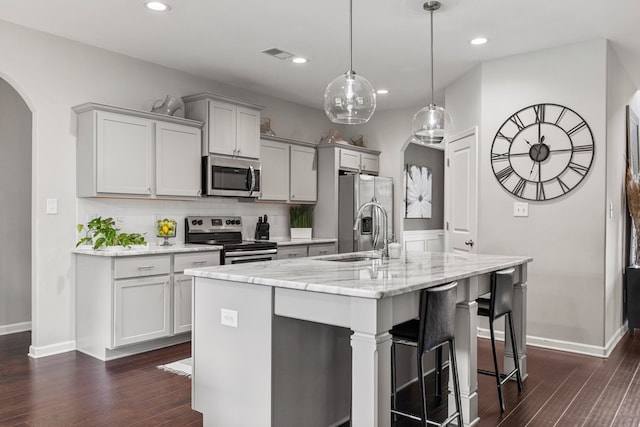 221 Abberly Ln, Ellerslie, GA 31807 - kitchen featuring stainless steel appliances, arched walkways, a center island with sink, a breakfast bar, and dark wood finished floors