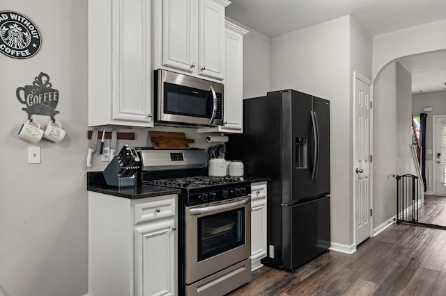 917 Dawkins Ct, Phenix City, AL 36867 - kitchen with appliances with stainless steel finishes, dark wood-style flooring, white cabinets, dark stone counters, and arched walkways