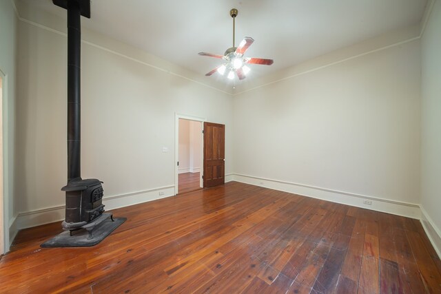 unfurnished living room featuring hardwood / wood-style floors, ceiling fan, and a wood stove