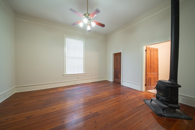 unfurnished living room featuring dark wood-type flooring, ceiling fan, and a wood stove