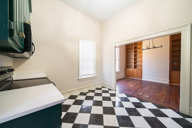 interior space with built in features, dark hardwood / wood-style flooring, ornamental molding, green cabinets, and electric range