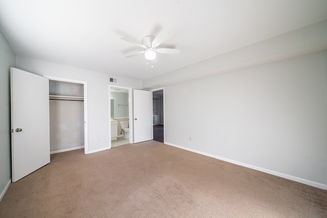 unfurnished bedroom featuring ceiling fan, carpet flooring, ensuite bath, and a closet