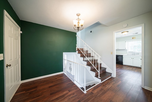 stairs with wood-type flooring, sink, and an inviting chandelier