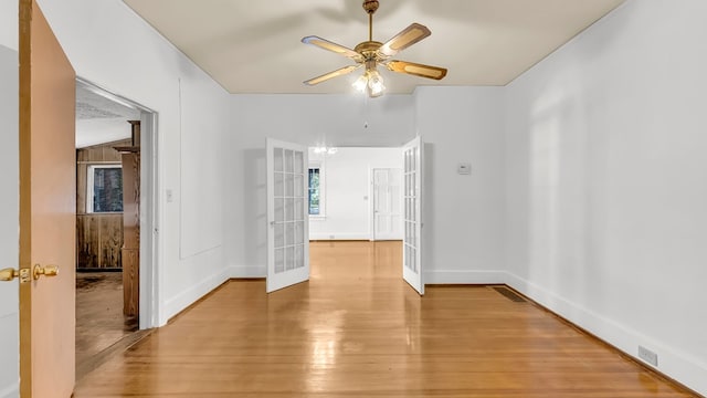 empty room with ceiling fan, light wood-type flooring, and french doors