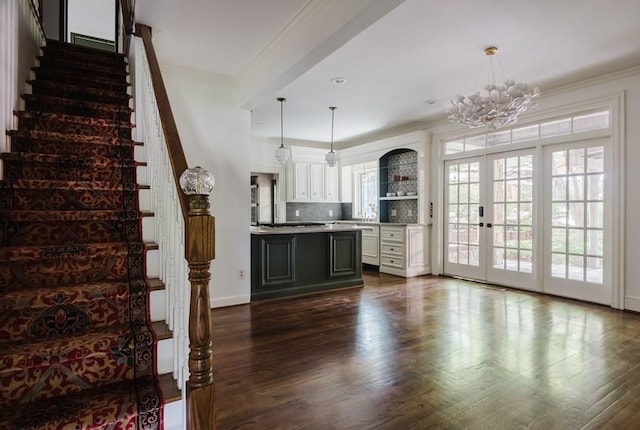 interior space with white cabinets, light countertops, ornamental molding, dark wood finished floors, and pendant lighting