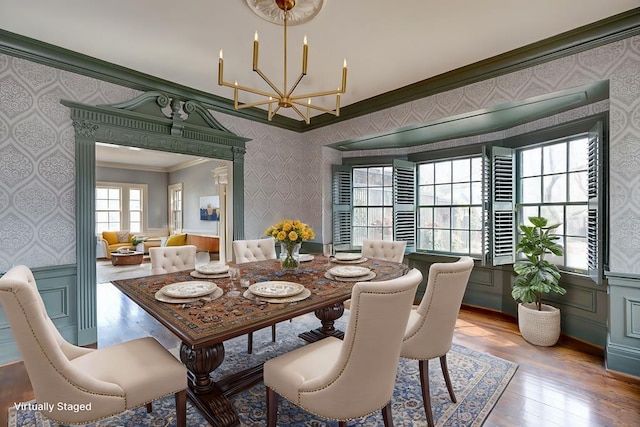 dining room featuring a chandelier, wainscoting, crown molding, and wallpapered walls