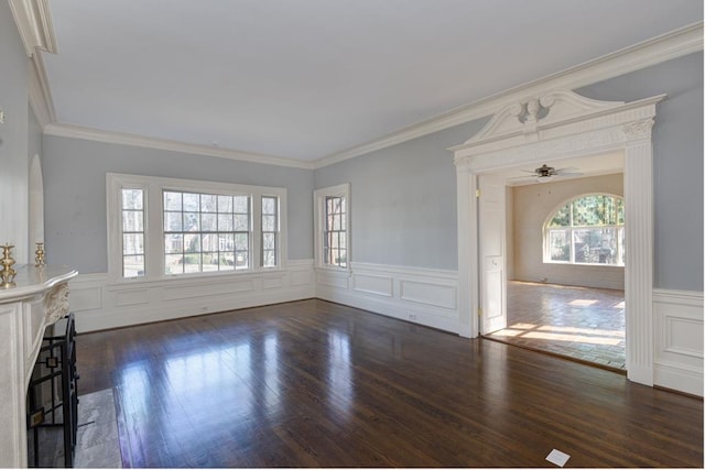 unfurnished living room featuring dark wood-type flooring, crown molding, a fireplace, and ceiling fan