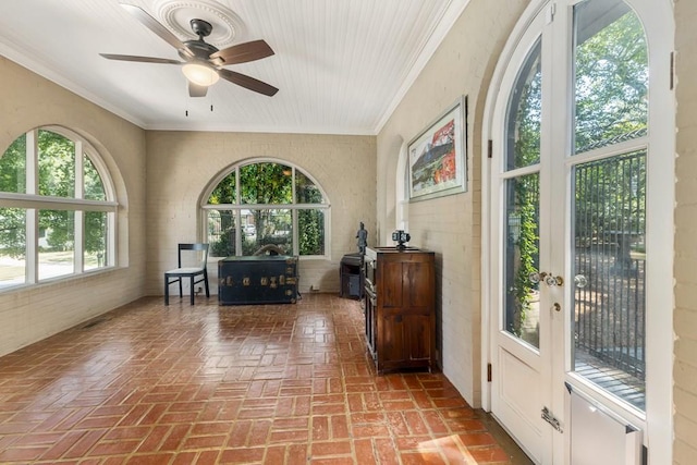 interior space with ceiling fan, brick floor, and crown molding