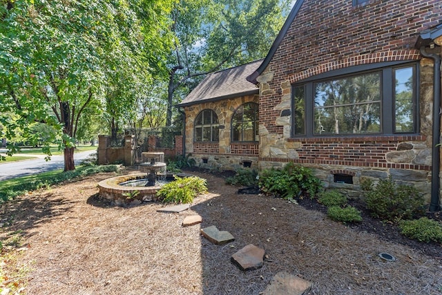 view of home's exterior with stone siding, brick siding, crawl space, and roof with shingles