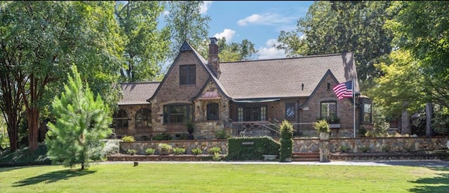 tudor home with a front yard and stone siding