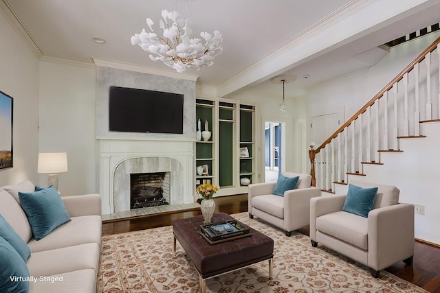 living area featuring a fireplace, an inviting chandelier, ornamental molding, wood finished floors, and stairs