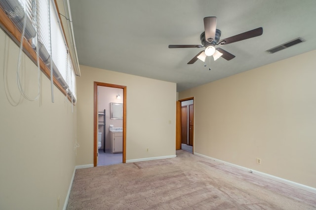 unfurnished bedroom featuring light colored carpet, visible vents, ensuite bathroom, ceiling fan, and baseboards