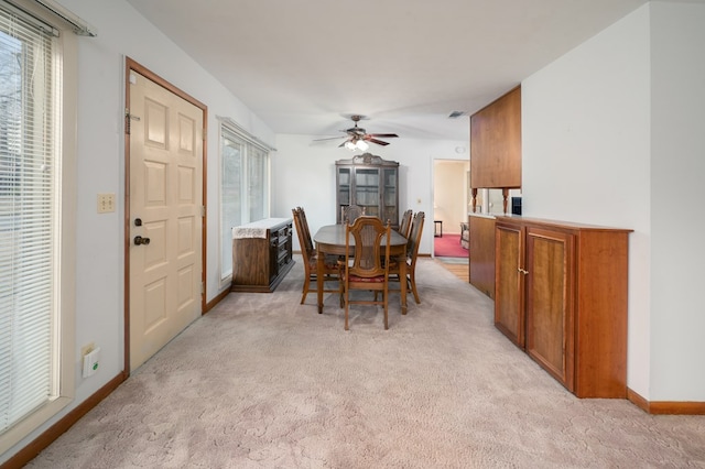 dining room featuring light carpet, ceiling fan, visible vents, and baseboards