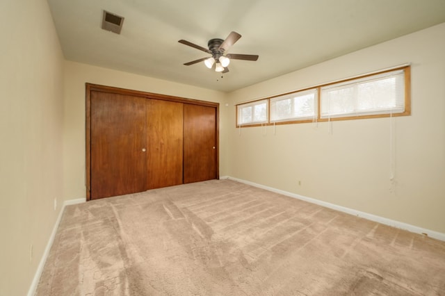 unfurnished bedroom featuring light colored carpet, a ceiling fan, baseboards, visible vents, and a closet