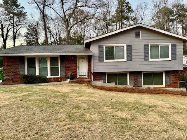 tri-level home featuring brick siding and a front yard