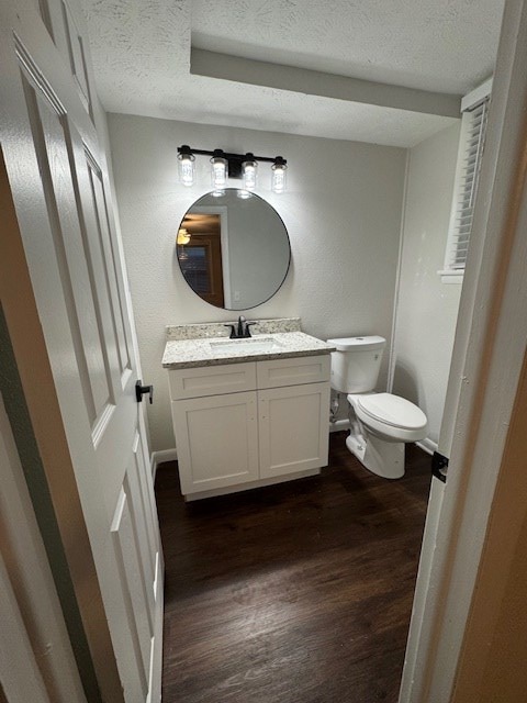 bathroom featuring vanity, wood finished floors, baseboards, a textured ceiling, and toilet