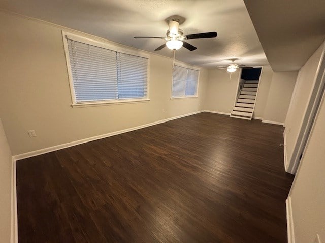 unfurnished living room with dark wood finished floors, stairway, ceiling fan, and baseboards