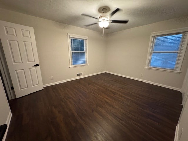 unfurnished bedroom featuring visible vents, dark wood-type flooring, a textured ceiling, baseboards, and ceiling fan