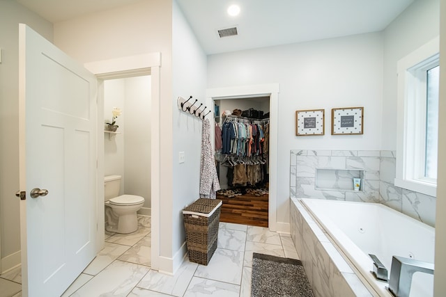 11602 Ga Highway 0085, Waverly Hall, GA 31831 - bathroom featuring marble look tile flooring, toilet, a jetted tub, baseboards, and a walk in closet