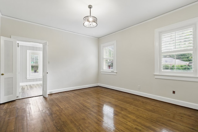 empty room with ornamental molding, healthy amount of natural light, wood finished floors, and baseboards