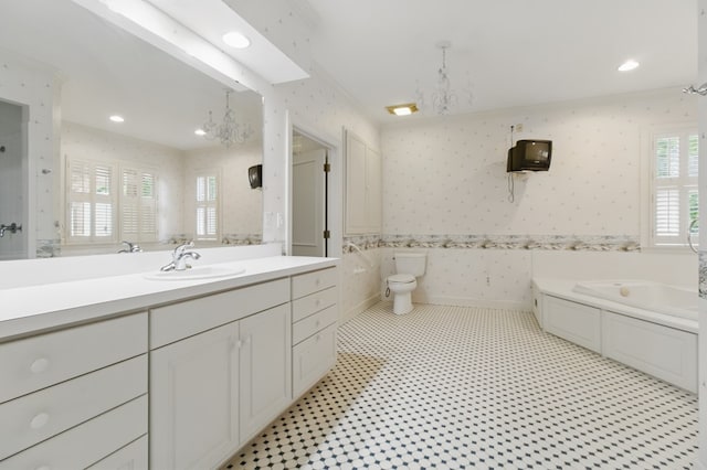bathroom featuring wallpapered walls, a garden tub, vanity, toilet, and a chandelier