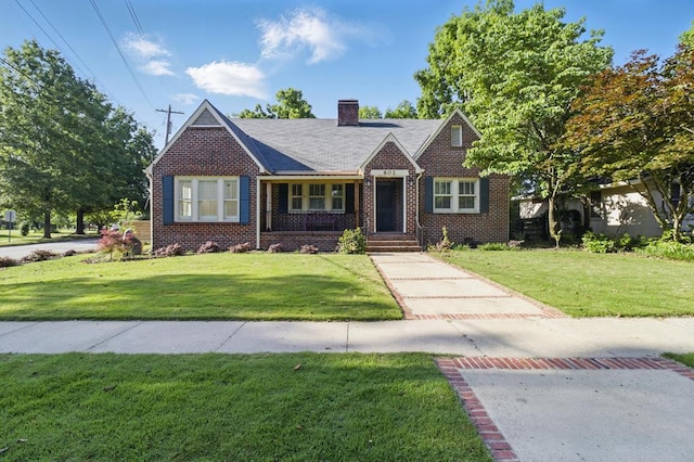 view of front facade with brick siding, a front yard, and a chimney