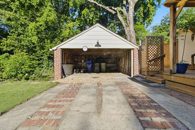 detached garage featuring fence and concrete driveway