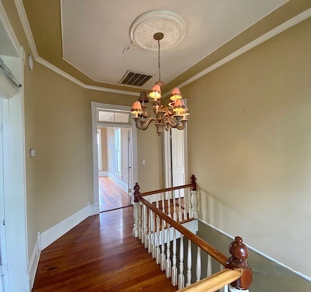 staircase featuring crown molding, hardwood / wood-style floors, and a chandelier