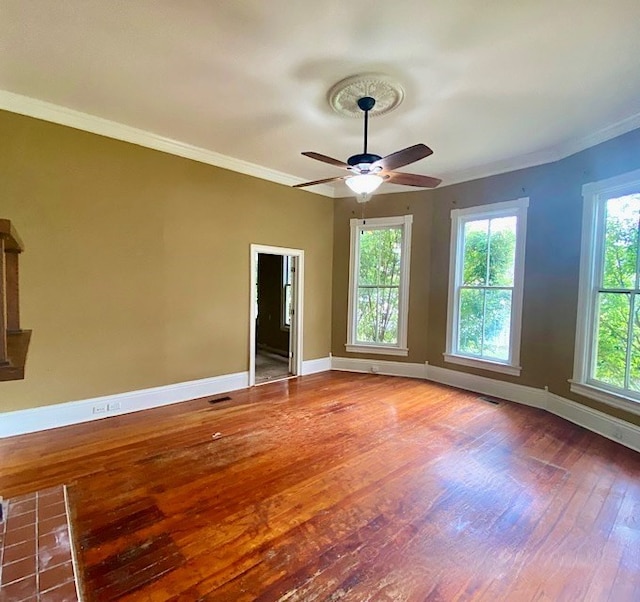 spare room featuring crown molding, a healthy amount of sunlight, and hardwood / wood-style flooring