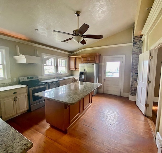 kitchen with a kitchen island, lofted ceiling, stainless steel appliances, and a wealth of natural light